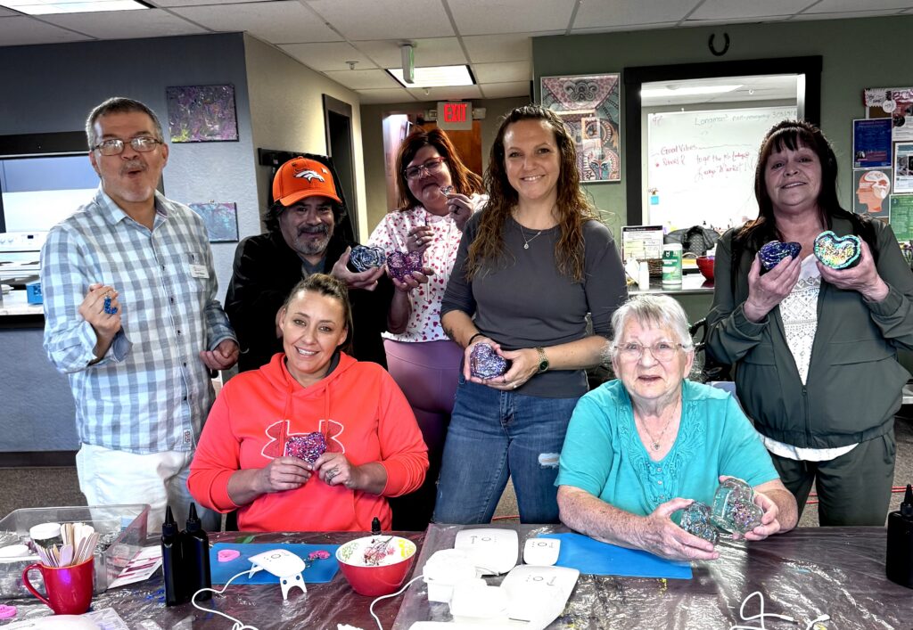 A group of RCL members proudly display their Resin Art made during a School for Recovery class.